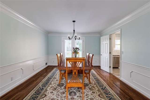 dining area with dark wood finished floors, a healthy amount of sunlight, a chandelier, and wainscoting