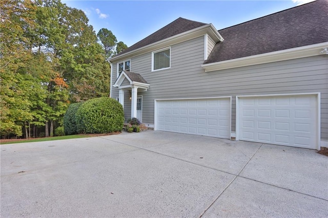 view of home's exterior featuring concrete driveway, a garage, and a shingled roof