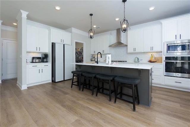 kitchen with white cabinets, stainless steel appliances, and wall chimney range hood