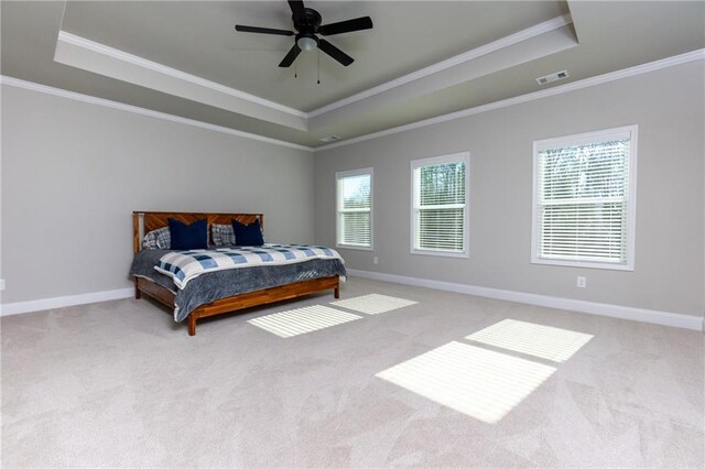 carpeted bedroom with ceiling fan, a raised ceiling, and crown molding