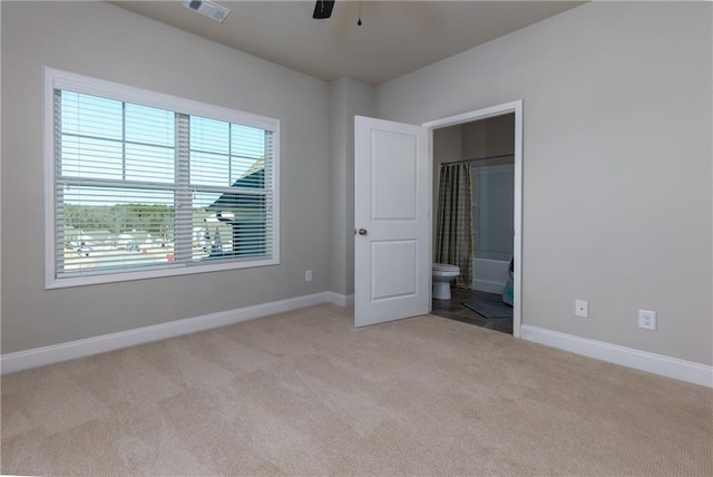 unfurnished bedroom with ceiling fan, light colored carpet, and connected bathroom