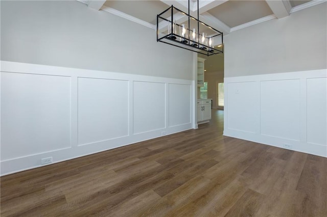 unfurnished dining area featuring beam ceiling, dark hardwood / wood-style flooring, an inviting chandelier, and ornamental molding