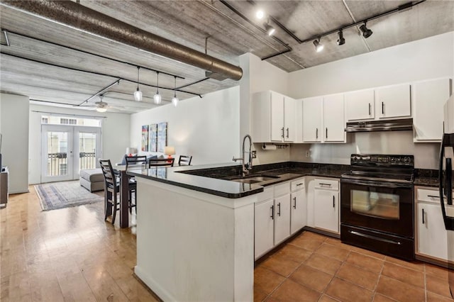 800 Peachtree St NE Unit 2304, Atlanta, GA 30308 - kitchen with electric range, under cabinet range hood, track lighting, a peninsula, and white cabinetry