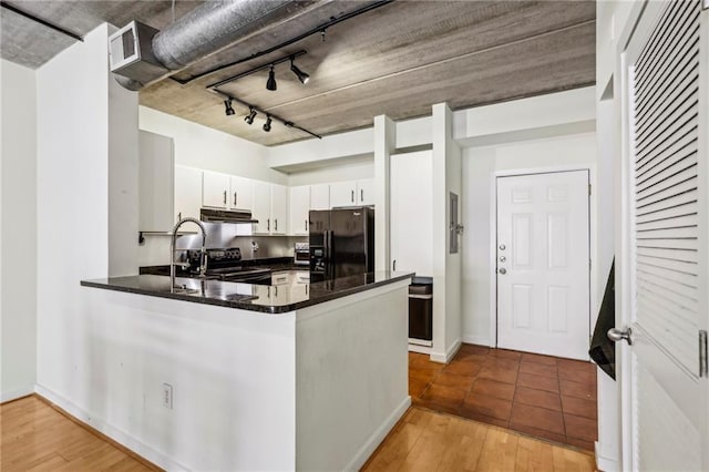 800 Peachtree St NE Unit 2304, Atlanta, GA 30308 - kitchen featuring black appliances, under cabinet range hood, a peninsula, dark countertops, and white cabinetry