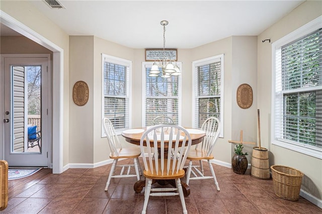 dining room with dark tile patterned floors and a chandelier