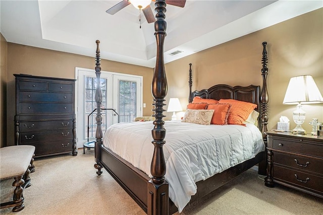 bedroom featuring ceiling fan, light colored carpet, and a tray ceiling