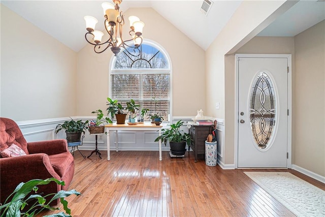 entrance foyer featuring vaulted ceiling, hardwood / wood-style floors, and a notable chandelier