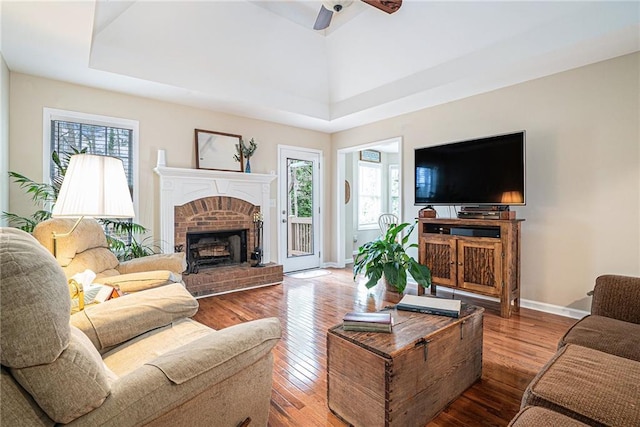 living room featuring ceiling fan, wood-type flooring, and a fireplace