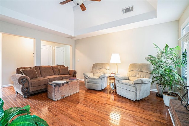 living room featuring hardwood / wood-style floors, ceiling fan, and a high ceiling