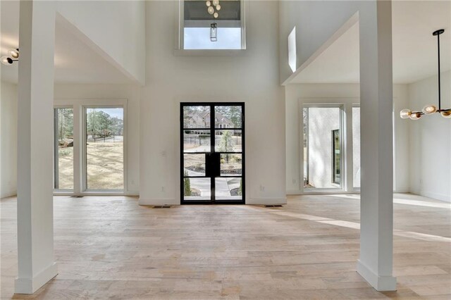 interior space with light hardwood / wood-style floors, a chandelier, and a high ceiling