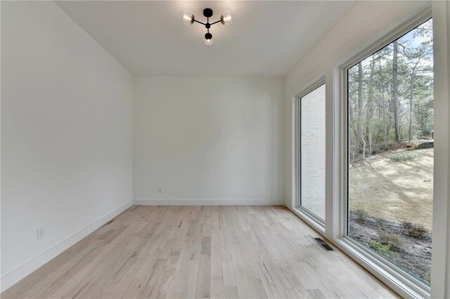 interior space with a notable chandelier, light hardwood / wood-style flooring, and a healthy amount of sunlight