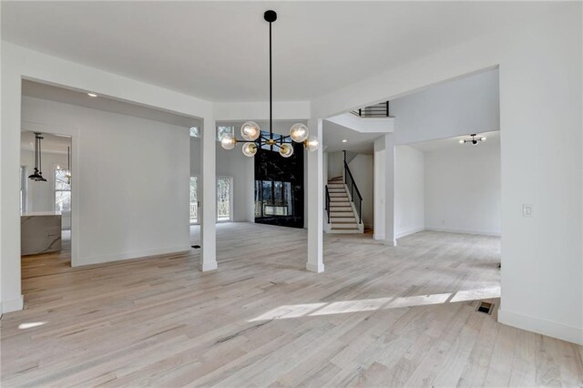 unfurnished living room with a high end fireplace, light hardwood / wood-style flooring, and a high ceiling