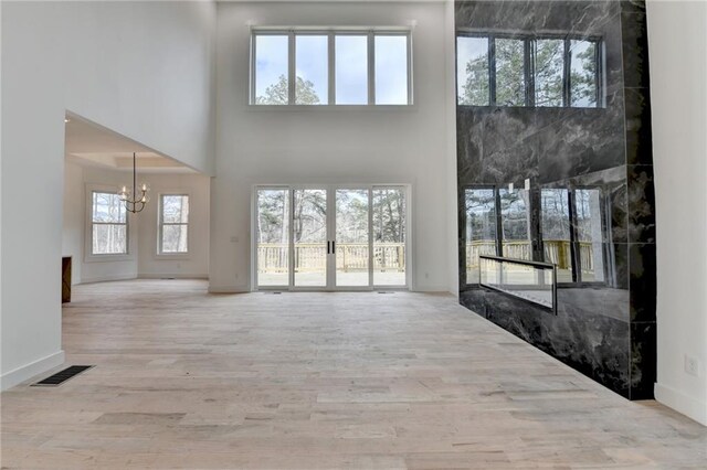 foyer featuring a chandelier, a high ceiling, and light wood-type flooring