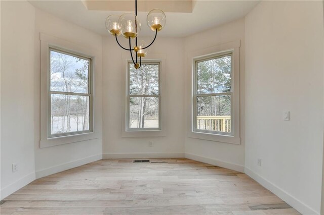 unfurnished dining area featuring plenty of natural light, light hardwood / wood-style floors, and a notable chandelier