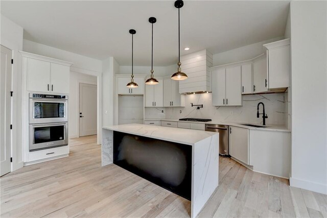 kitchen featuring sink, white cabinetry, decorative light fixtures, a kitchen island, and stainless steel appliances