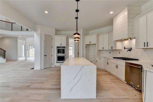 kitchen with a kitchen island, appliances with stainless steel finishes, decorative light fixtures, sink, and white cabinets