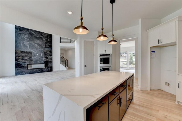 kitchen with appliances with stainless steel finishes, decorative light fixtures, white cabinets, backsplash, and a center island