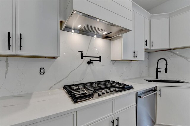 kitchen featuring white cabinetry, hanging light fixtures, a kitchen island, stainless steel appliances, and light stone countertops