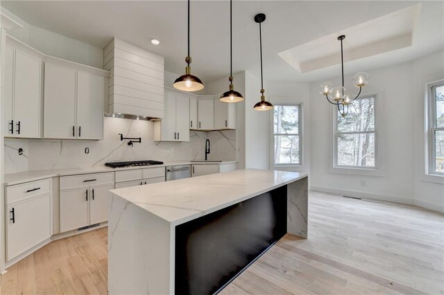 kitchen featuring stainless steel gas cooktop, sink, white cabinets, and range hood