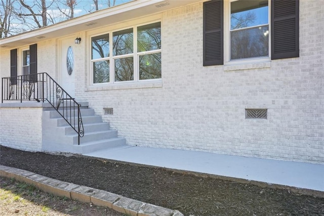 property entrance featuring brick siding and crawl space