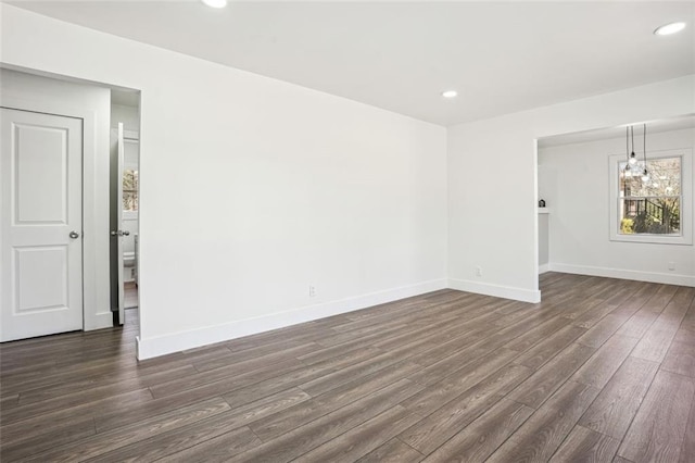 spare room with dark wood-type flooring, recessed lighting, and baseboards