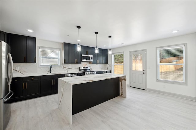 kitchen with plenty of natural light, a kitchen island, stainless steel appliances, and hanging light fixtures