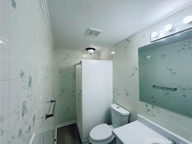 bathroom featuring tile walls, vanity, a shower with shower door, and toilet