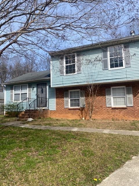 tri-level home with brick siding and a front lawn