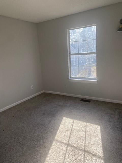 empty room with baseboards, visible vents, and carpet floors