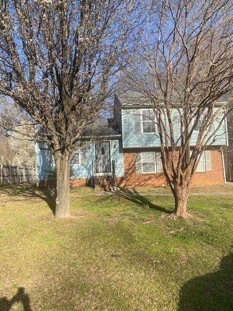 tri-level home with a front lawn and fence