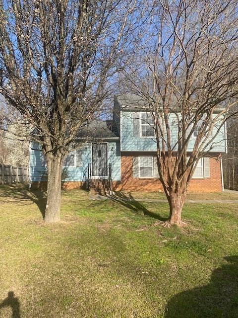 split level home featuring a front lawn and fence