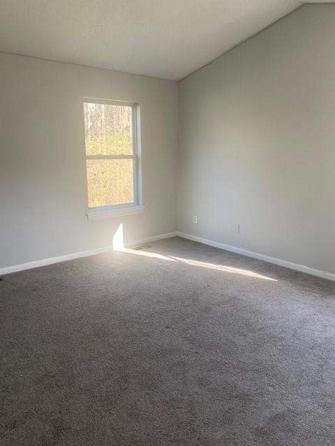 spare room featuring baseboards and dark carpet
