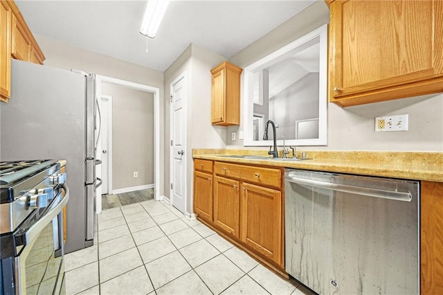 kitchen featuring appliances with stainless steel finishes, light tile patterned floors, lofted ceiling, and sink