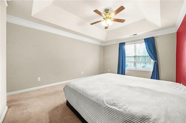 carpeted bedroom with a tray ceiling, ceiling fan, and ornamental molding