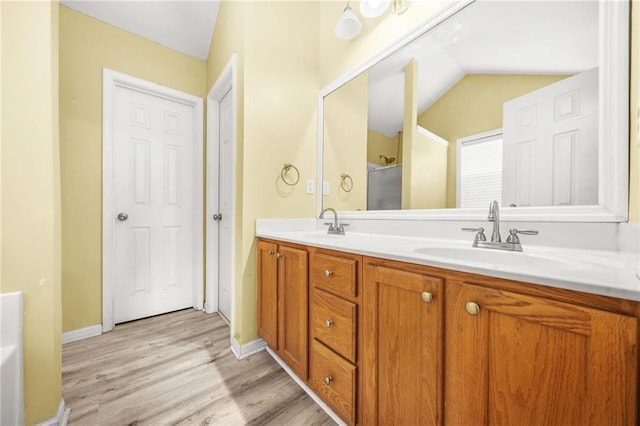 bathroom with wood-type flooring, vanity, and vaulted ceiling