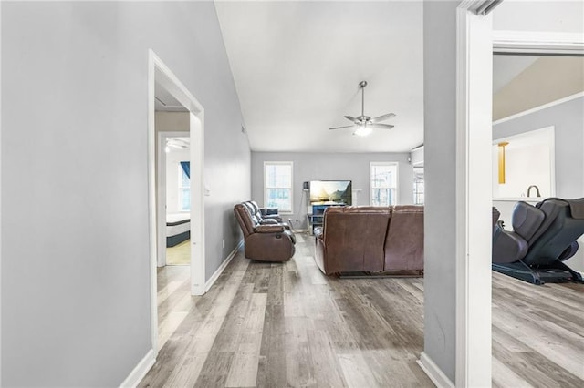 living room featuring vaulted ceiling, light hardwood / wood-style flooring, and ceiling fan