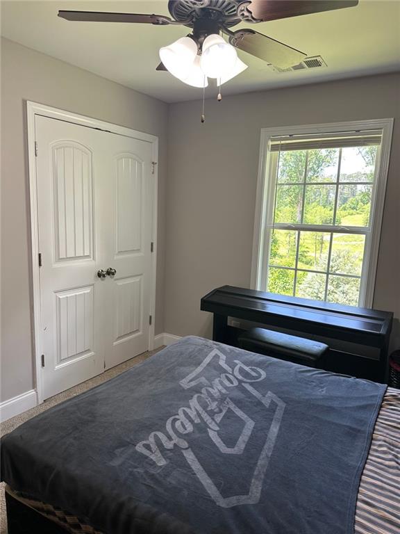 bedroom with baseboards, visible vents, and ceiling fan