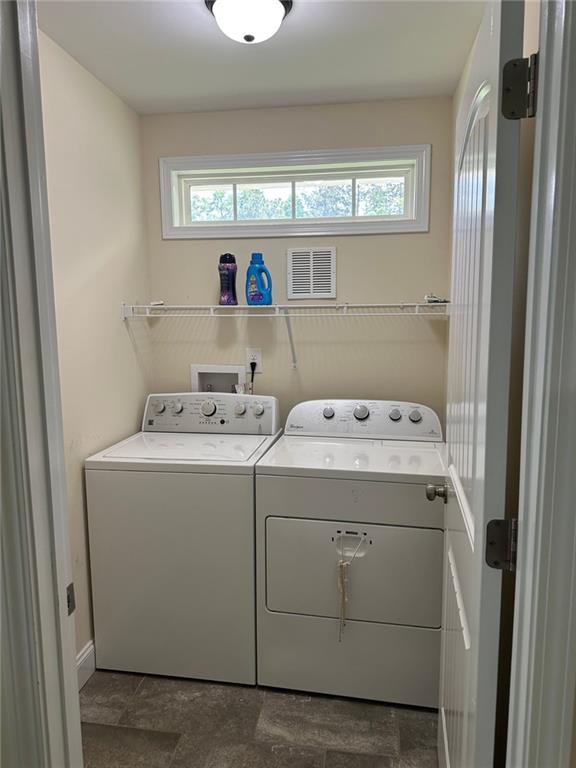 laundry area featuring laundry area, separate washer and dryer, stone finish floor, baseboards, and visible vents