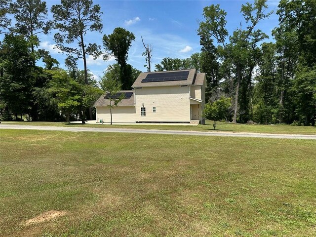 view of home's exterior with roof mounted solar panels and a yard