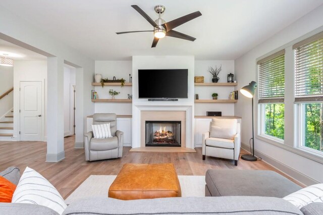 1013 Liberty Springs Dr, Woodstock, GA 30188 - living room with a warm lit fireplace, stairs, ceiling fan, and light wood-type flooring