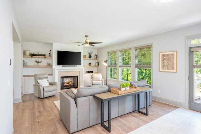 1013 Liberty Springs Dr, Woodstock, GA 30188 - living area with a glass covered fireplace, ceiling fan, light wood-style floors, and baseboards