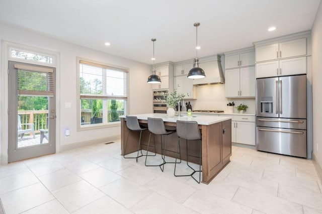 1013 Liberty Springs Dr, Woodstock, GA 30188 - kitchen featuring stainless steel appliances, premium range hood, light countertops, a kitchen breakfast bar, and a kitchen island with sink