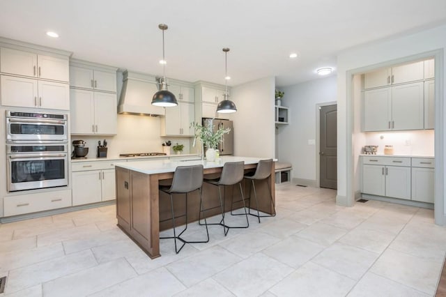 1013 Liberty Springs Dr, Woodstock, GA 30188 - kitchen featuring appliances with stainless steel finishes, light countertops, custom exhaust hood, a breakfast bar area, and an island with sink