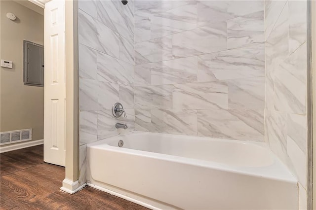 bathroom featuring electric panel, hardwood / wood-style flooring, and tiled shower / bath