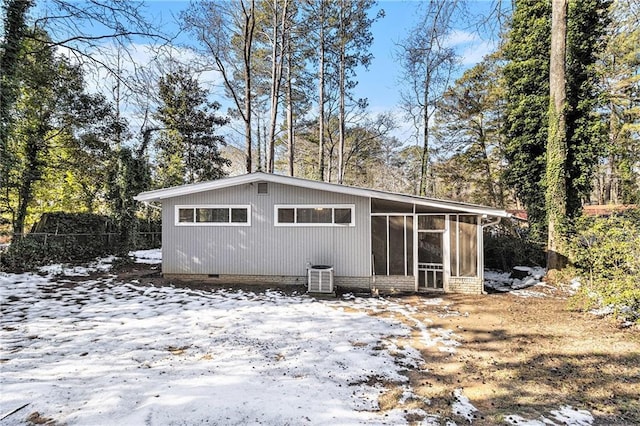 snow covered back of property featuring central AC and a sunroom