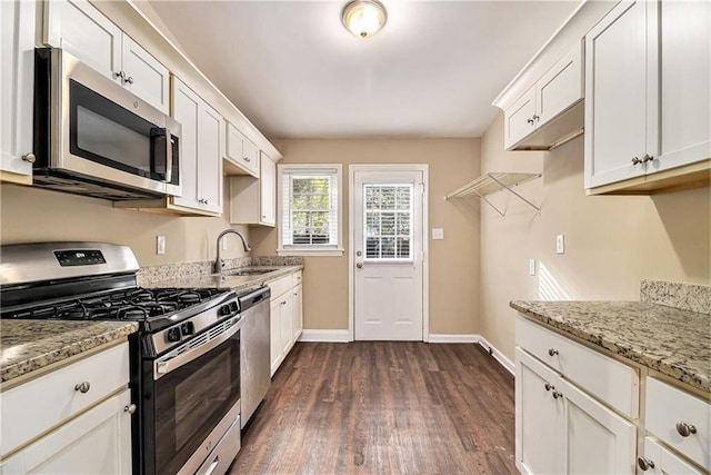 kitchen with white cabinets, stainless steel appliances, dark hardwood / wood-style flooring, light stone counters, and sink