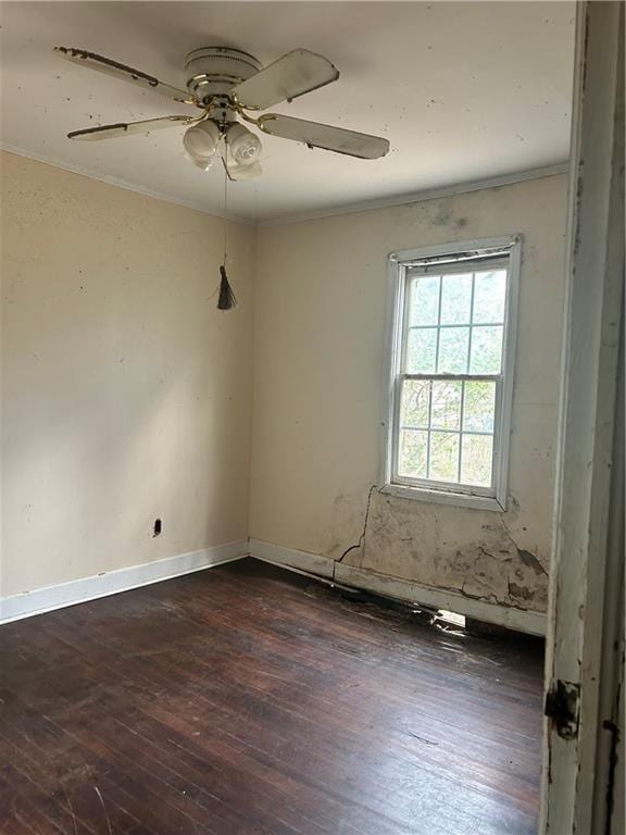 empty room with dark wood-style floors, crown molding, baseboards, and ceiling fan