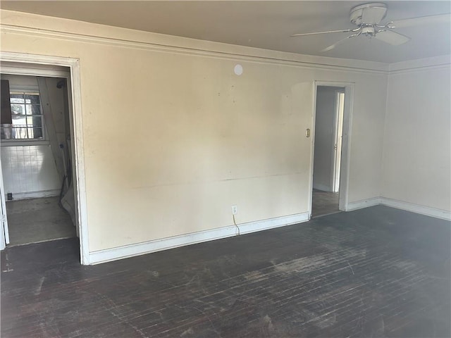 empty room featuring ceiling fan, baseboards, and dark wood finished floors