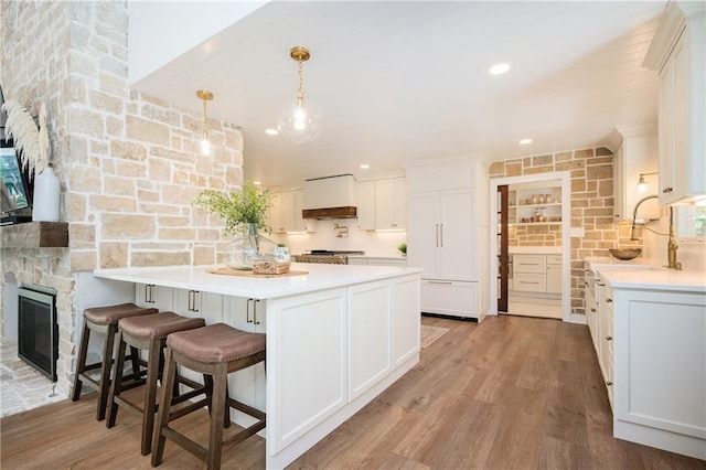 12410 Charlotte Dr, Alpharetta, GA 30004 - kitchen featuring white cabinetry, wood finished floors, a peninsula, and light countertops