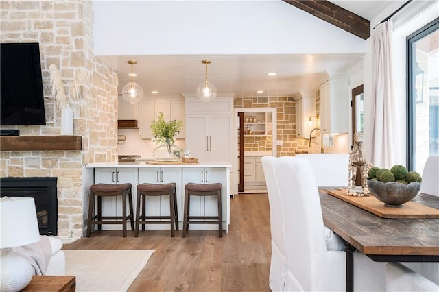 12410 Charlotte Dr, Alpharetta, GA 30004 - kitchen featuring a stone fireplace, a kitchen breakfast bar, light wood-type flooring, white cabinets, and a peninsula